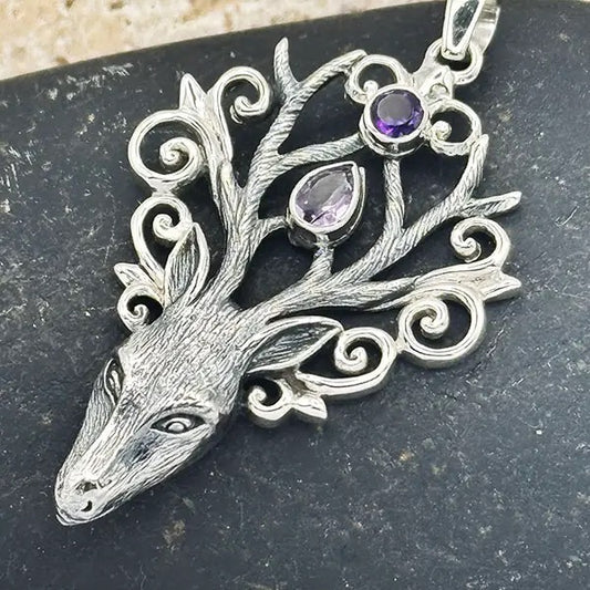 Silver deer head pendant with gemstones on a dark surface