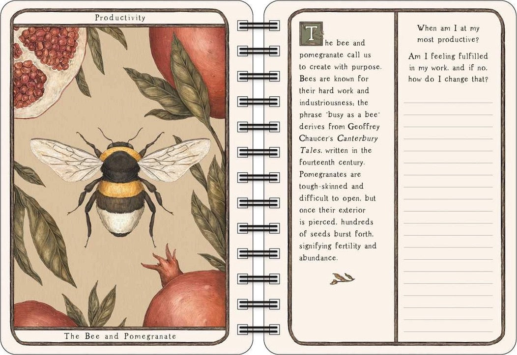 An open spiral-bound notebook showing a vintage-style illustration of a bee and pomegranate on the left page, with text prompts and lined writing space on the right page.