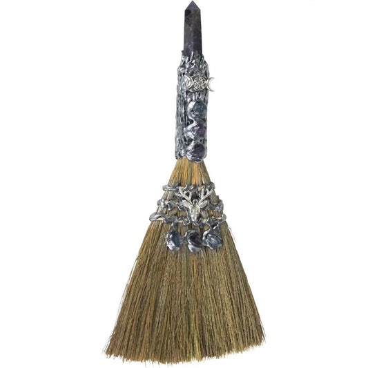 Decorative broom with silver embellishments on a white background