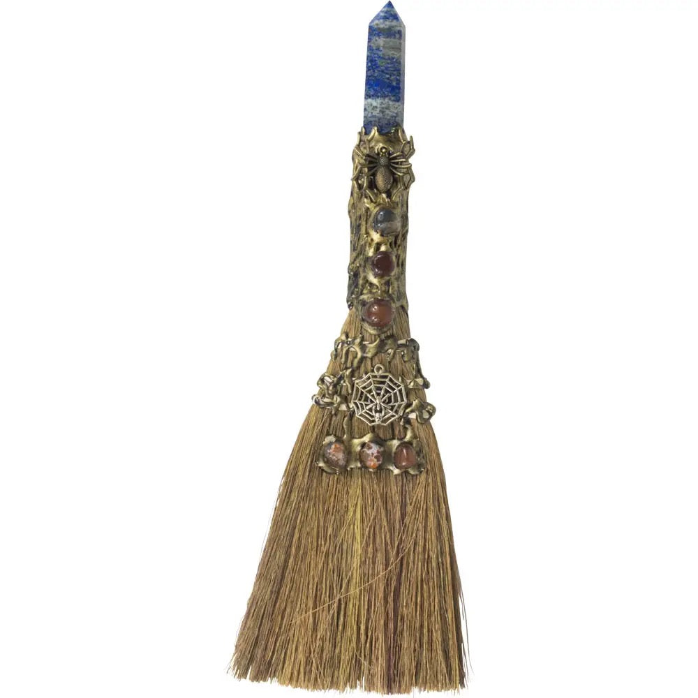 Decorative broom with gemstones and a crystal on a white background