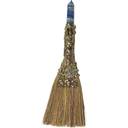 Decorative broom with gemstones and a crystal on a white background