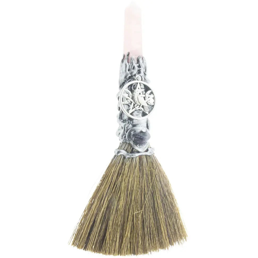 Decorative broom with a silver handle and black bristles on a white background
