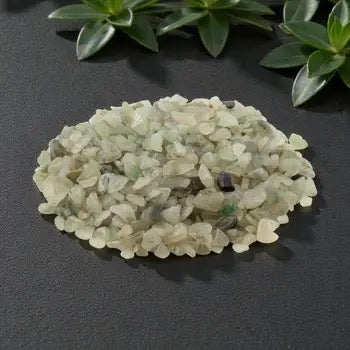 Green crystal stones on a dark surface with green plants in the background