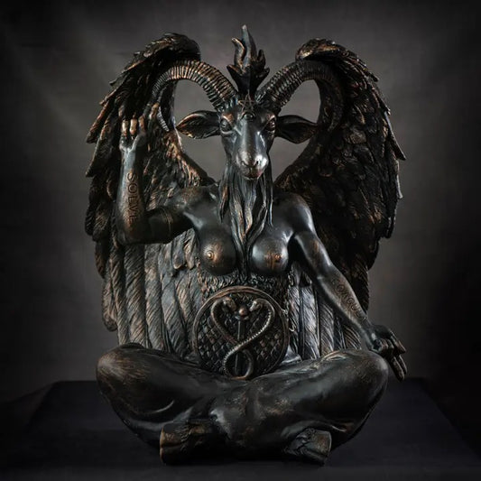 A dark bronze-finished statue of a winged goat-like female figure seated cross-legged, photographed against a dark studio background.