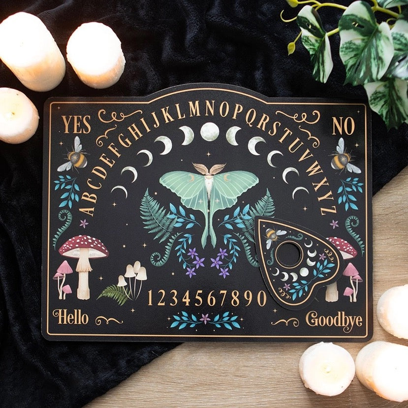 Decorative board with alphabet, numbers, and nature-themed designs on a dark surface with candles and plants.