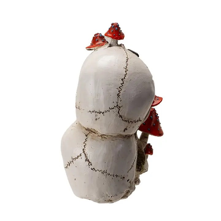 Statue back of two skulls with red mushrooms on a white background.