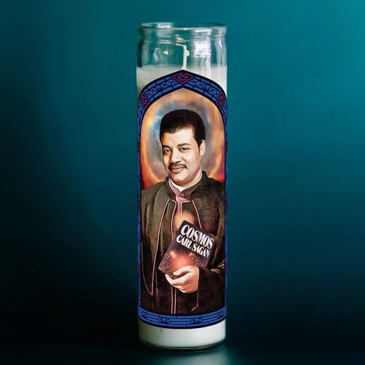 Candle with a portrait of Carl Sagan and 'Cosmos' logo on a dark background