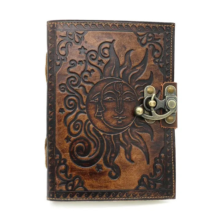 Brown leather journal with sun and moon design and brass lock on a white background