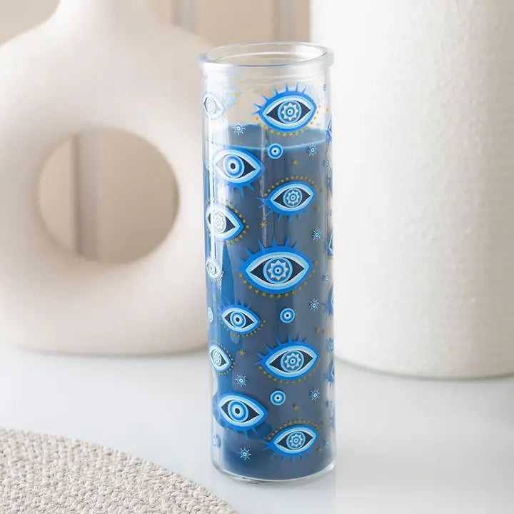 Glass candle holder with blue eye pattern on a white surface