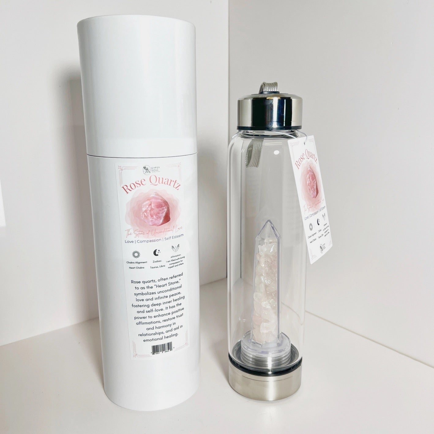 Clear water bottle with rose quartz crystal and packaging on a white background