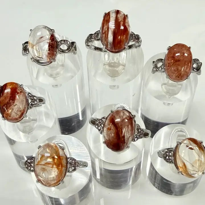 Set of rings with brown gemstones on clear stands against a white background