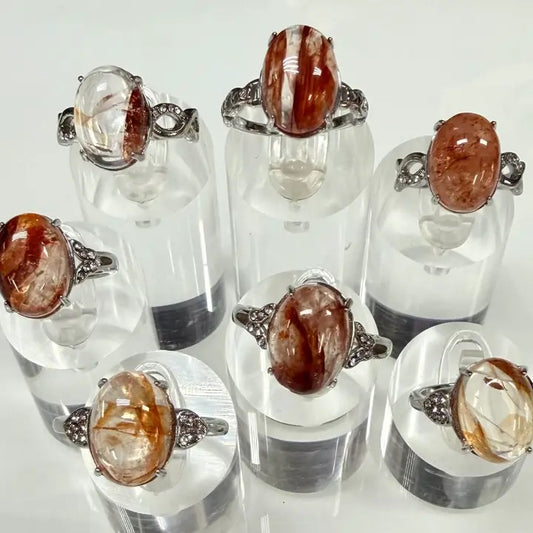 Set of rings with brown gemstones on clear stands against a white background