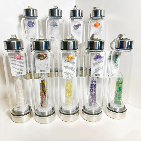 Set of clear water bottles with silver lids, each containing different colored stones or crystals.