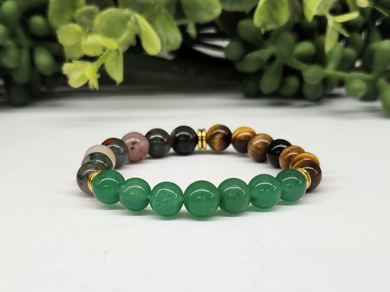 Multicolored beaded bracelet on a white surface with greenery in the background