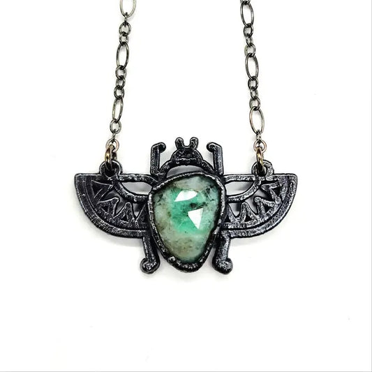 scarab necklace with green stone on a white background