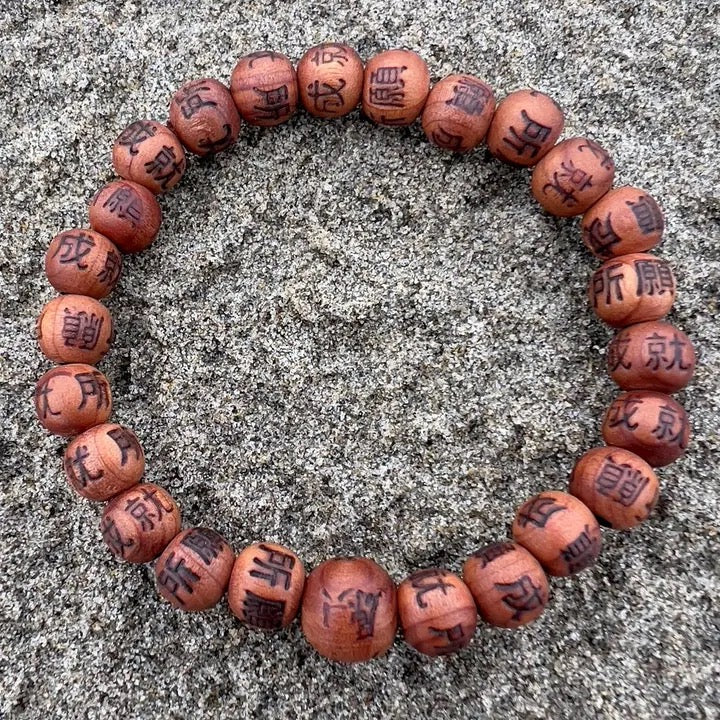 Wooden beaded bracelet with engraved characters on a textured surface