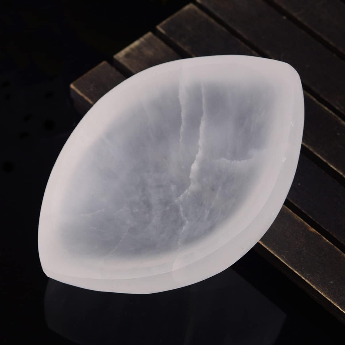 Selenite bowl with a leaf-shaped design on a dark wooden surface
