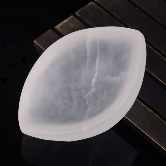 Selenite bowl with a leaf-shaped design on a dark wooden surface
