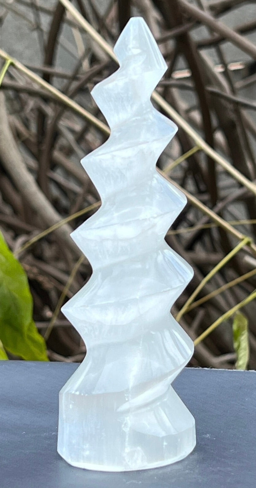Crystal-like tower sculpture on a dark surface with a natural background