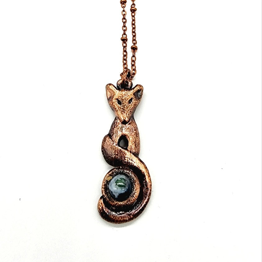 Copper fox pendant with a green stone on a white background