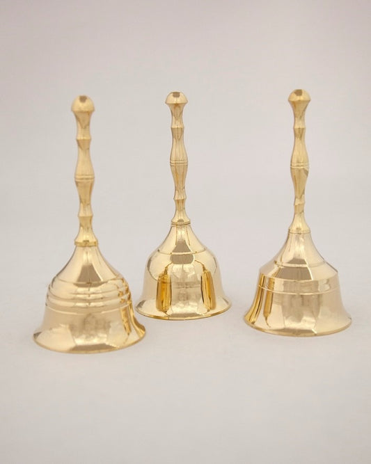 Three gold bells with textured handles on a light gray background