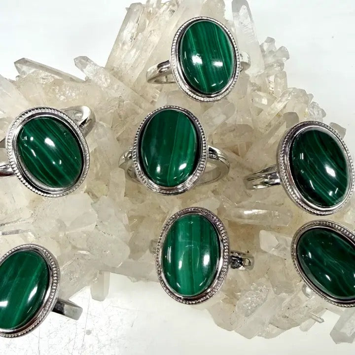 Set of green gemstone rings with silver settings on a crystal background