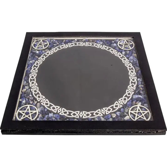 A square black-framed mirror with a mystical design. The inner surface features a large black circular center, surrounded by a white Celtic knot border and four white pentagrams set against a background of blue and purple stones.