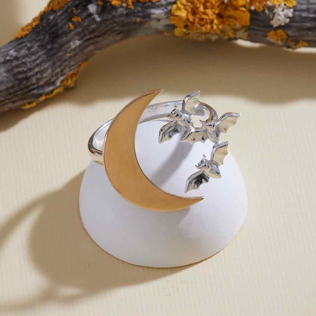 Decorative item with a gold crescent moon and silver bats shapes on a white base.