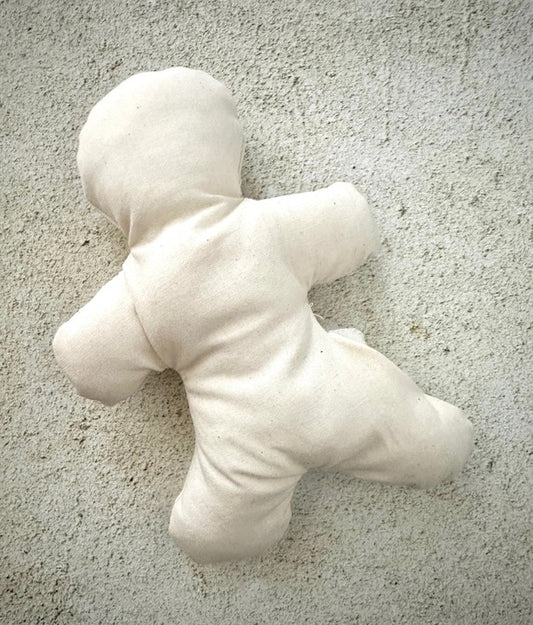 Unfinished white doll stuffed figure on a textured gray surface