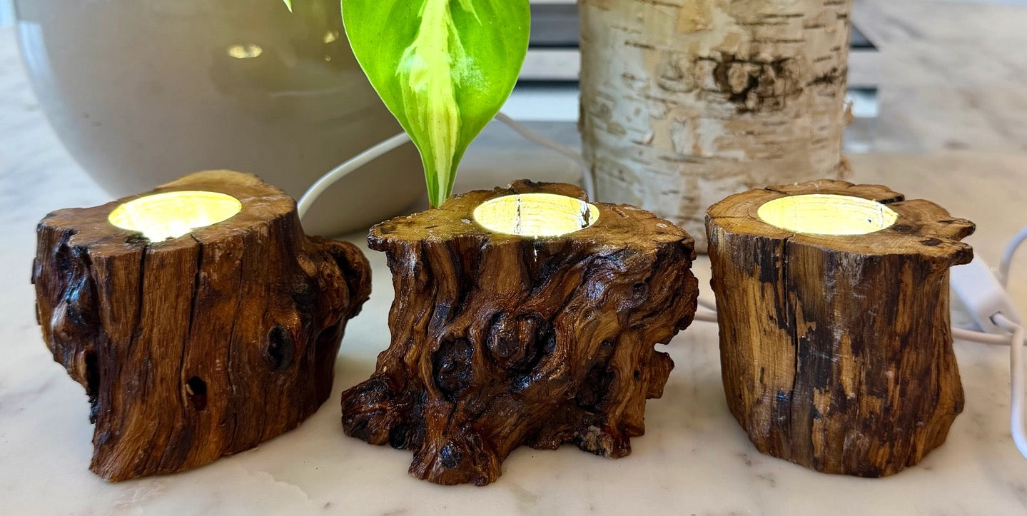 Three wooden candle holders with candles on a marble surface.