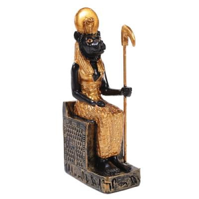 Statue of a seated figure with a gold head and black body, holding a staff on a white background.