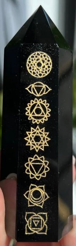 Black crystal with gold chakra symbols on a dark background