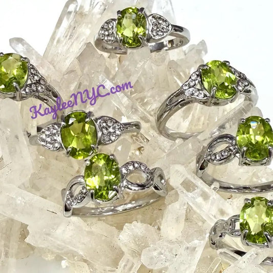 Silver rings with green gemstones on a crystal background, featuring the brand 'KayleeNYC.com'.