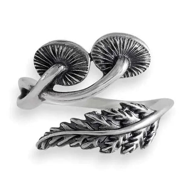 Silver ring with mushroom and fern designs on a white background