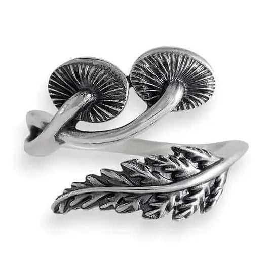 Silver ring with mushroom and fern designs on a white background