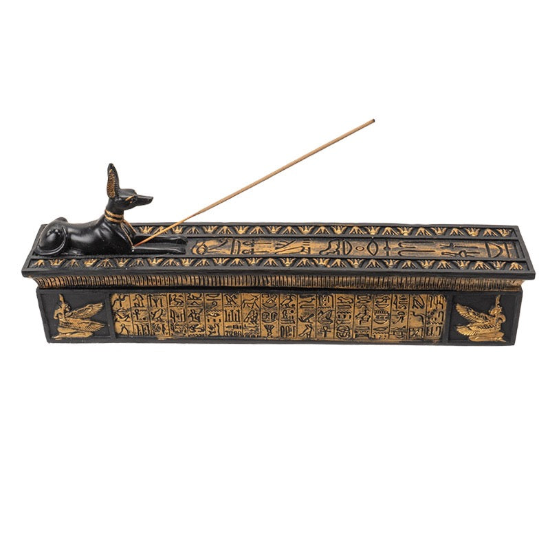 Decorative incense burner with Egyptian hieroglyphics and a burning stick on a white background