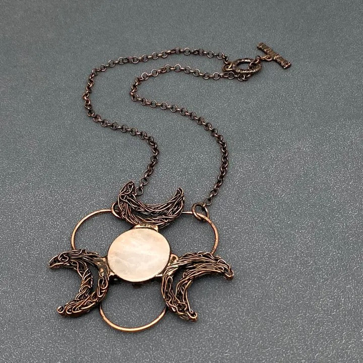 Bronze necklace with a circular pendant on a gray background back of pendant
