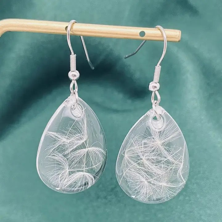 Teardrop-shaped earrings with leaf-like designs on a green background
