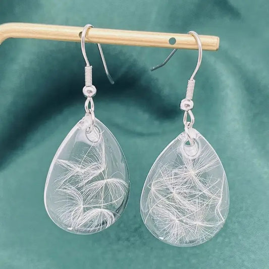 Teardrop-shaped earrings with leaf-like designs on a green background