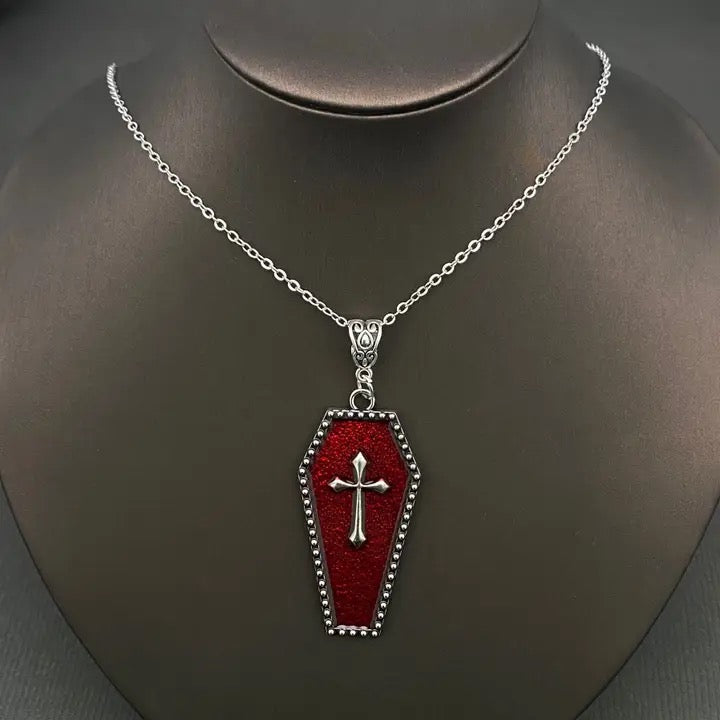 Red coffin-shaped pendant with a silver cross on a mannequin neck.