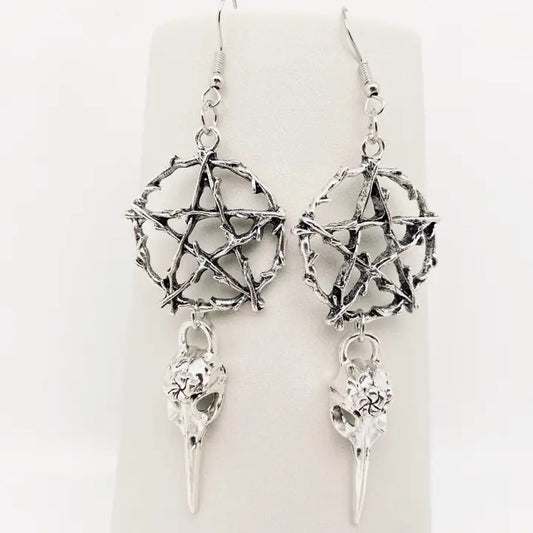 Silver pentagram earrings with bird skull pendants on a white background