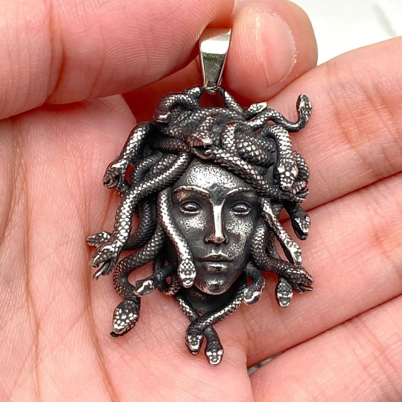 Silver Medusa pendant held in a hand