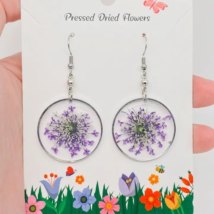 Pressed dried flower earrings on a decorative card with floral illustrations.