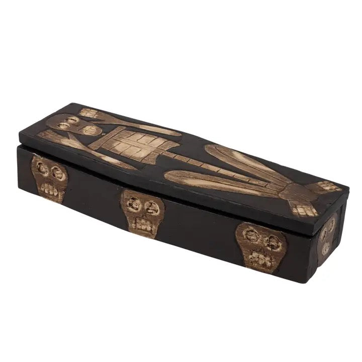 A coffin-shaped decorative box with a black finish and raised gold-toned Egyptian-style artwork, including a pharaoh and skull details, shown on a plain white background.