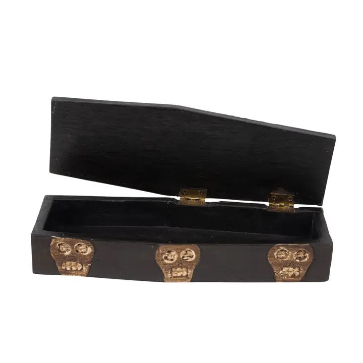 A black coffin-shaped decorative box with an open lid, featuring three gold skull ornaments on the front and small gold hinges, shown on a plain white background.
