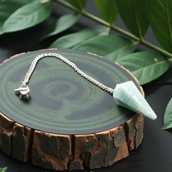 green pendulum on a wooden surface with leaves in the background