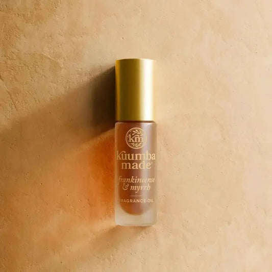 Fragrance oil bottle with gold cap on a beige background
