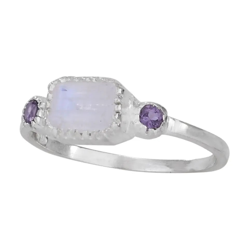 Silver ring with a moonstone and two purple gemstones on a white background