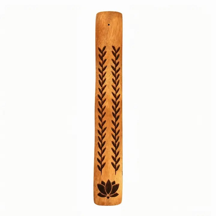 A rectangular wooden incense burner with a natural light brown finish, featuring two vertical columns of dark engraved leaf-like motifs and a dark lotus symbol near the bottom, shown against a plain white background.
