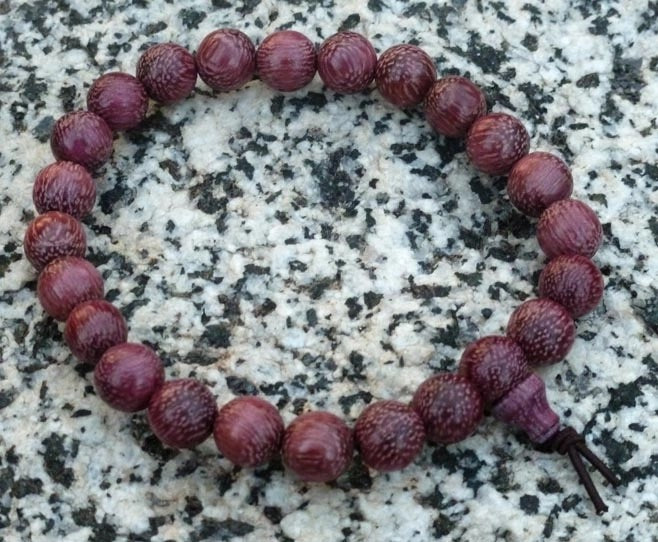 Purple beaded bracelet on a textured stone surface